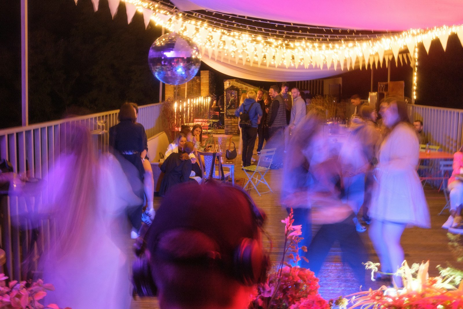 Guests enjoying a lively garden party with beautifully presented food under string lights.